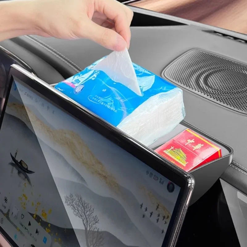 Black leather car dashboard organizer holding blue facial tissue pack and red small box.