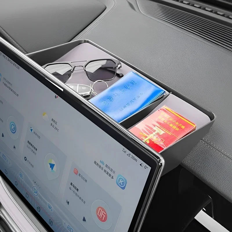 Black leather dashboard storage tray holding sunglasses, a blue book, and a red card.