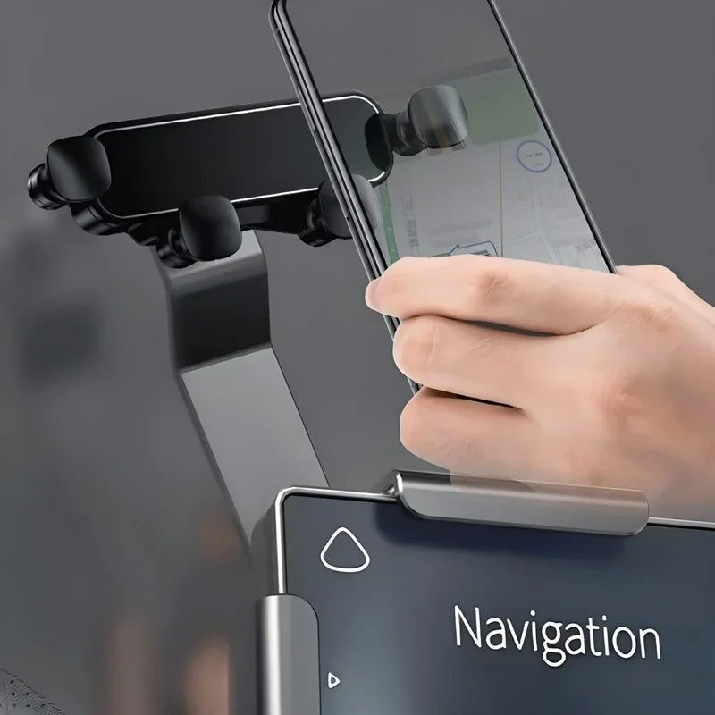 A hand holding a smartphone with a navigation map next to a black adjustable car phone mount installed on a dashboard.