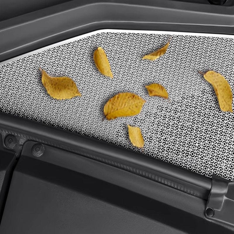 Close-up of a grey textured car interior mat with scattered potato chips.