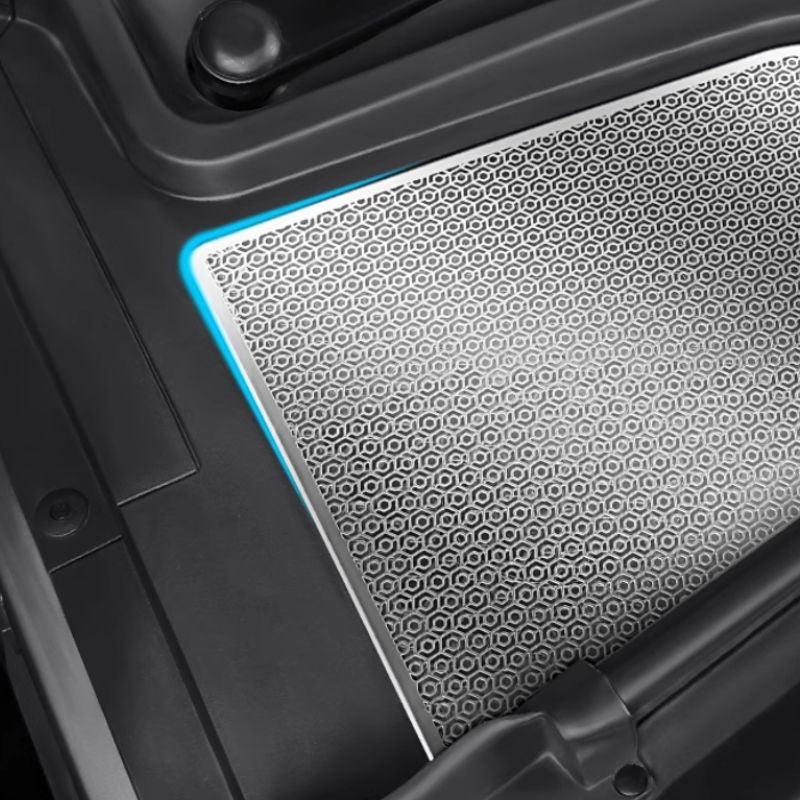 Close-up of a silver honeycomb patterned car floor mat with blue ambient lighting.