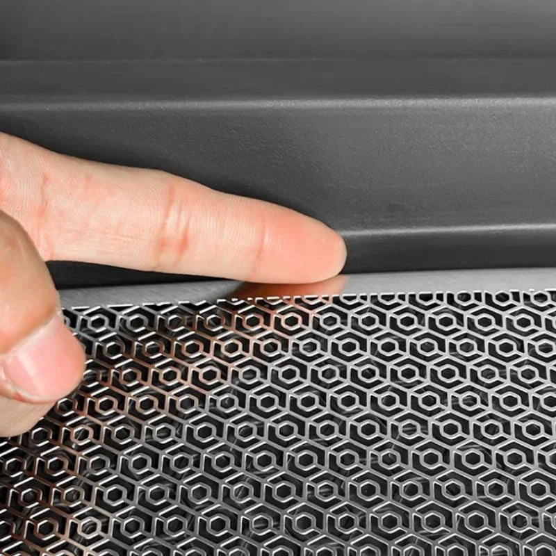 Close-up of a hand touching a silver metallic honeycomb pattern car accessory.