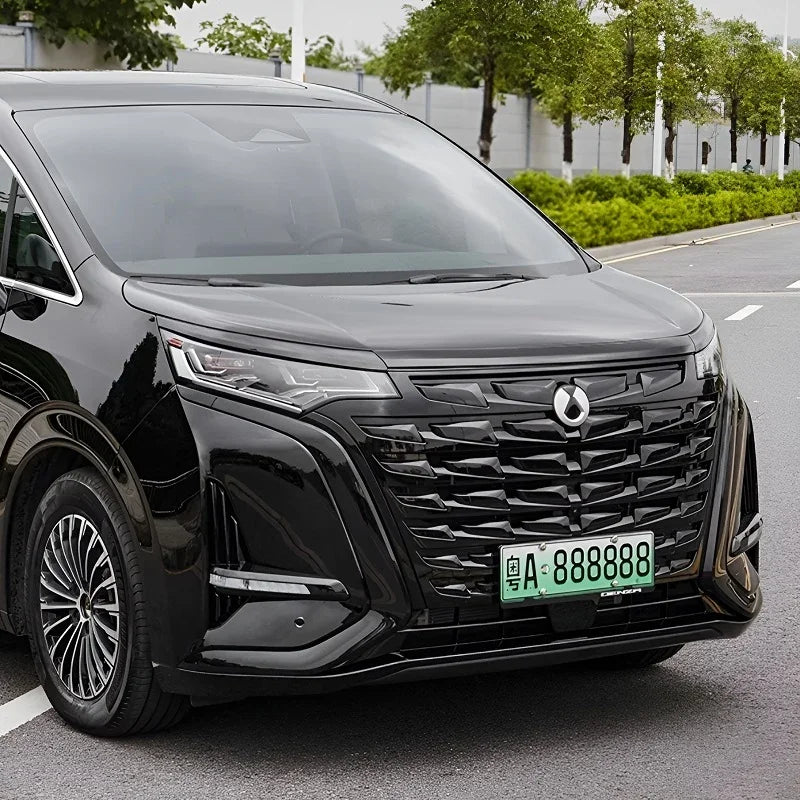 Glossy black BYD Denza MPV featuring a large textured grille and sleek LED headlights.