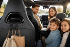 Family of four sitting inside a car with a view of nature outside.