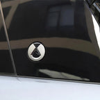 Close-up of a silver chrome BYD emblem mounted on a sleek black car body.