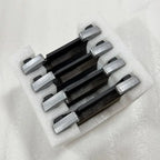 Set of four premium black ceramic brake pads with silver metallic backing plates in protective foam.