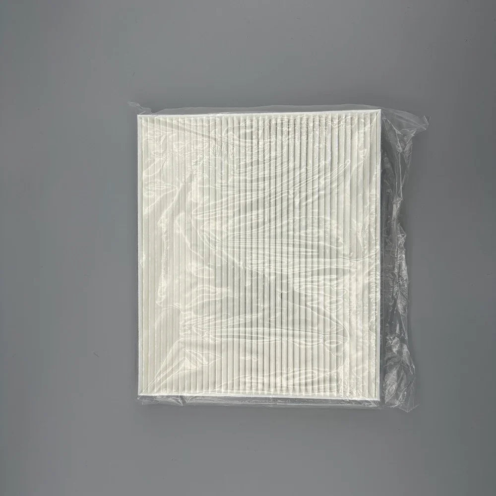 White pleated cabin air filter in protective clear plastic packaging.