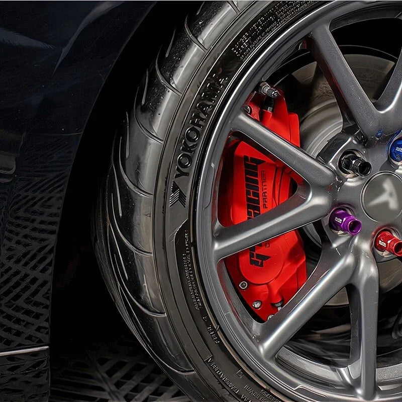 Close-up of a high-performance car wheel with red brake calipers and grey alloy rims.