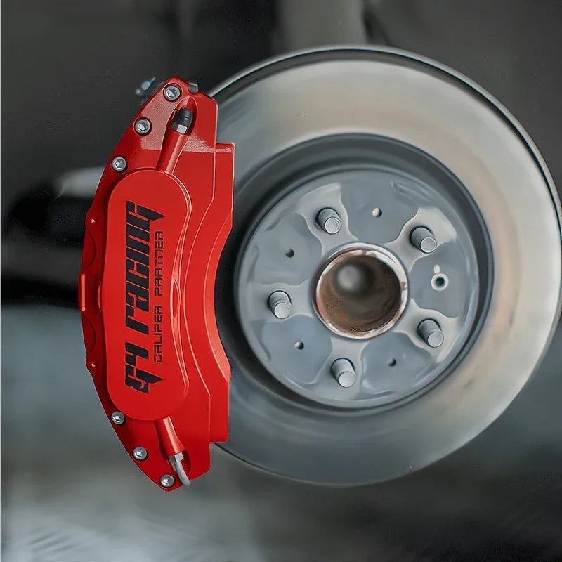 Professional red aluminum racing brake caliper cover installed on a car disc brake rotor.