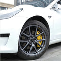 White car featuring dark grey multi-spoke alloy wheels and bright yellow high-performance brake calipers.