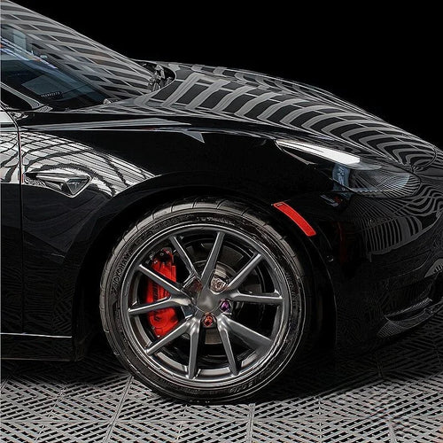 Glossy black car exterior featuring premium dark grey multi-spoke alloy wheels and red brake calipers.