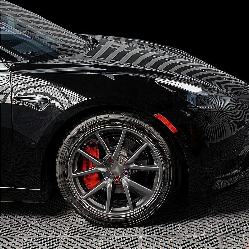 Glossy black car featuring premium dark grey multi-spoke alloy wheels with striking red brake calipers.