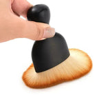 Professional black matte makeup brush with soft orange-tinted synthetic bristles.