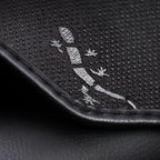 Close-up of black textured leather material featuring a silver lizard emblem design.