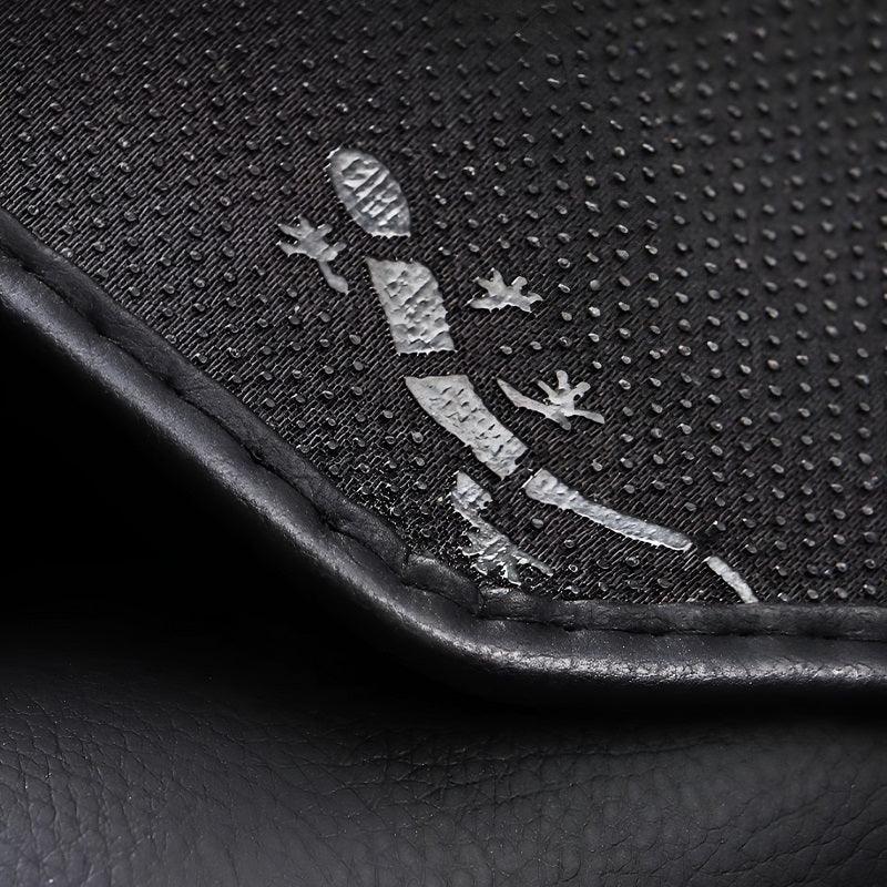 Close-up of black textured leather material featuring a silver lizard emblem design.