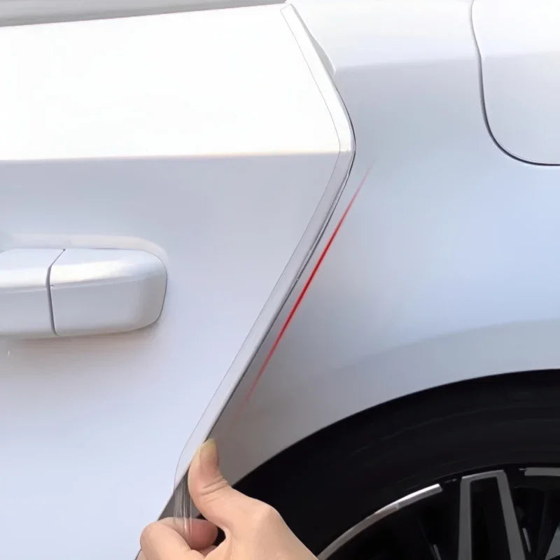 Transparent paint protection film being applied to a white car fender with a red guide line.