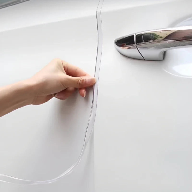 Hand applying a clear, transparent protective paint protection film to a white car door.