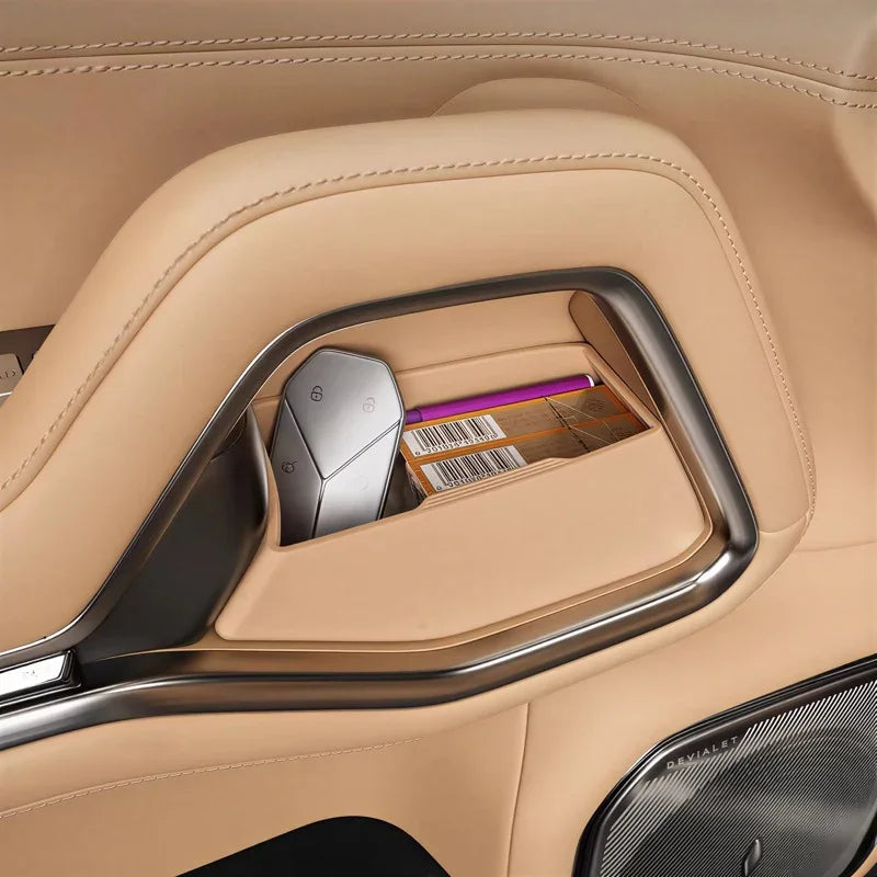Tan leather car door storage compartment with chrome trim, key fob and accessories.