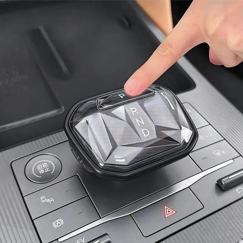 Hand pressing a crystal clear gear shifter cover with a diamond-cut pattern for BYD cars.