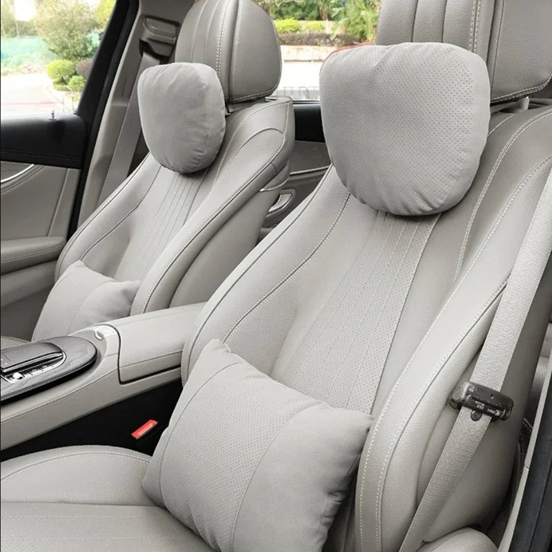 Light grey perforated leather headrest and lumbar support cushions for car seats.