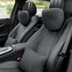 Black perforated leather car neck and lumbar support pillows installed on vehicle seats.