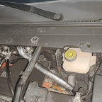 Close-up of a car engine bay featuring a silver heat-shielded component and fluid reservoir.