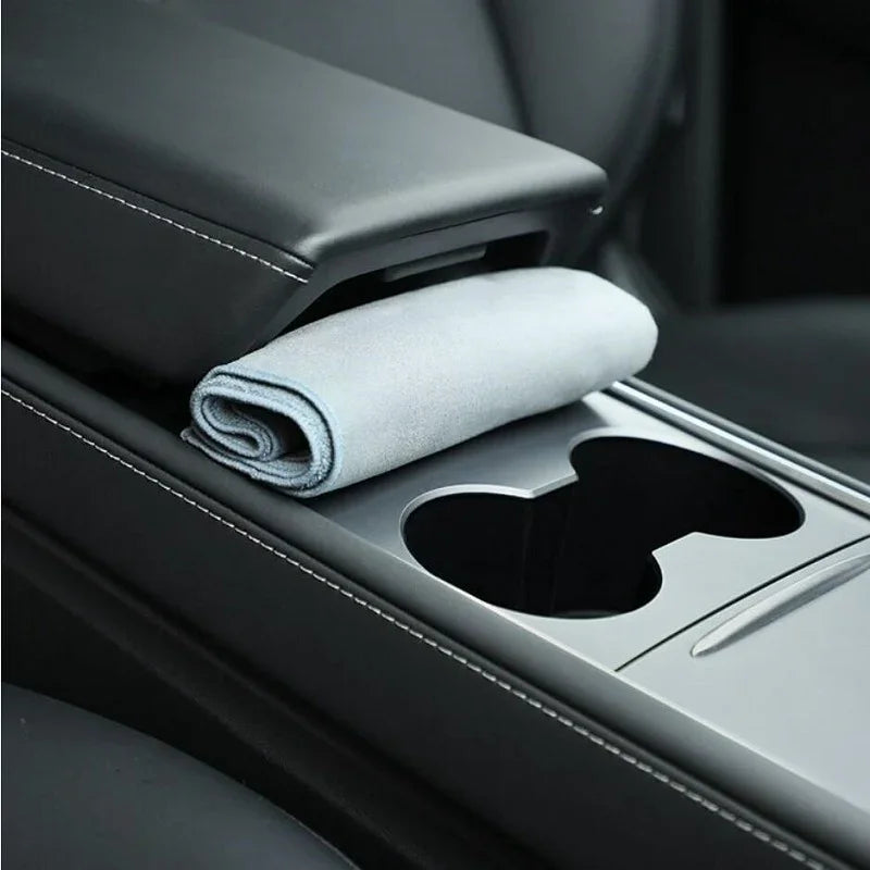 Light gray microfiber cleaning cloth tucked in a black leather car center console compartment.