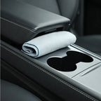 Light gray microfiber cleaning cloth tucked in a black leather car center console compartment.