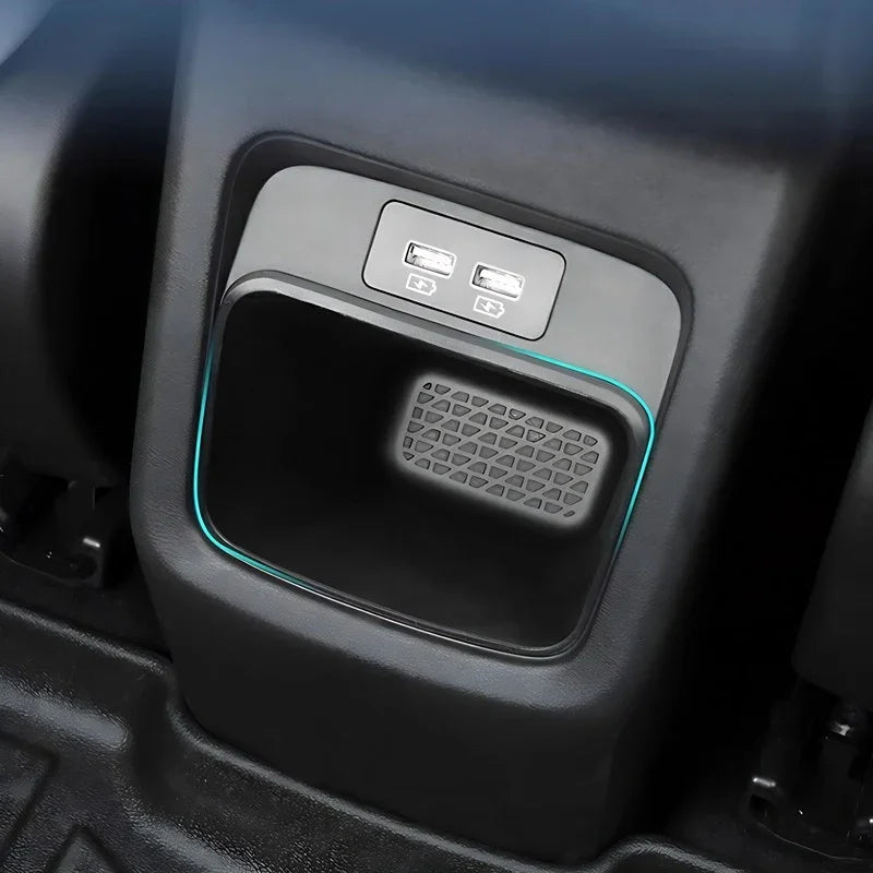 Black interior car storage compartment featuring dual USB charging ports and blue LED accent lighting.