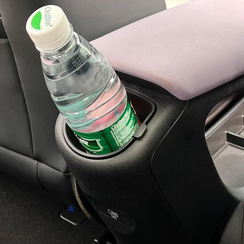 Black textured car console cup holder containing a plastic water bottle.