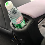 Black textured car console cup holder containing a plastic water bottle.