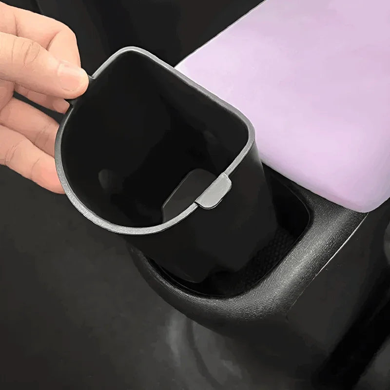 Black durable plastic car cup holder insert being placed in center console.