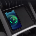 Black textured wireless charging pad with a smartphone charging in a car center console.