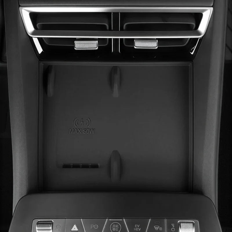 Black matte wireless charging pad with 50W max power icon in a car center console.