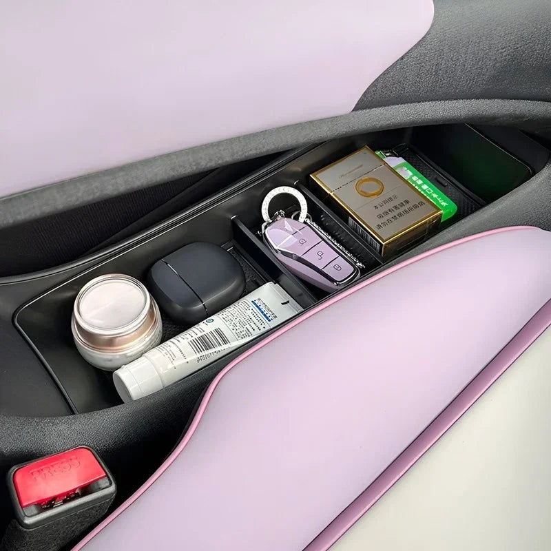 Black organizer tray in a lavender car interior holding a key fob, cosmetic jar, and small items.