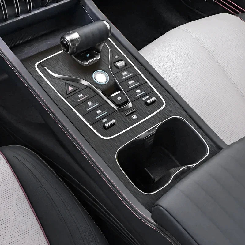 Modern car center console with black leather, silver accents, and a glossy gear shifter.