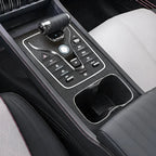 Modern car center console with black leather, silver accents, and a glossy gear shifter.