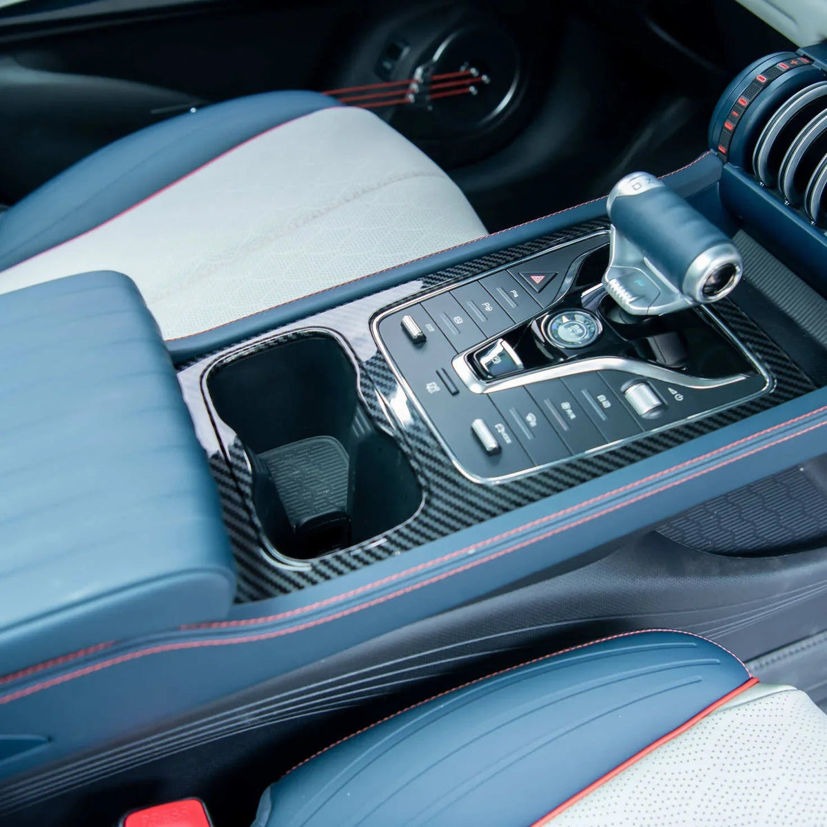 Blue and white leather car interior with red stitching and carbon fiber center console