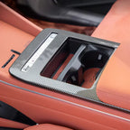 Carbon fiber center console trim with integrated cup holders in a luxury tan leather interior.
