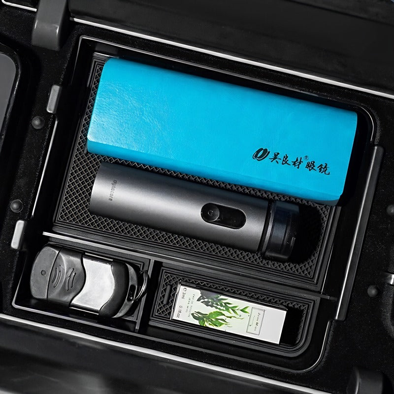 Blue textured leather organizer and grey metallic thermos in a black car storage compartment.