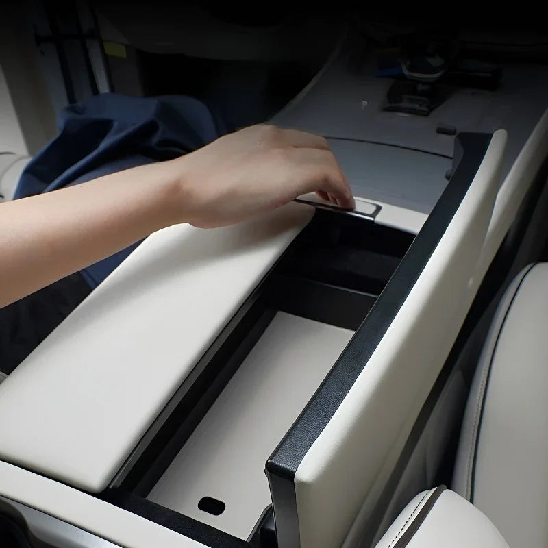 Hand opening a white leather center console organizer with black trim for a car interior.