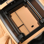 Professional tan leather center console organizer tray with black trim for vehicle interior.