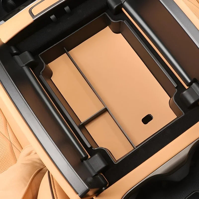 Professional tan leather center console organizer tray with black trim for vehicle interior.