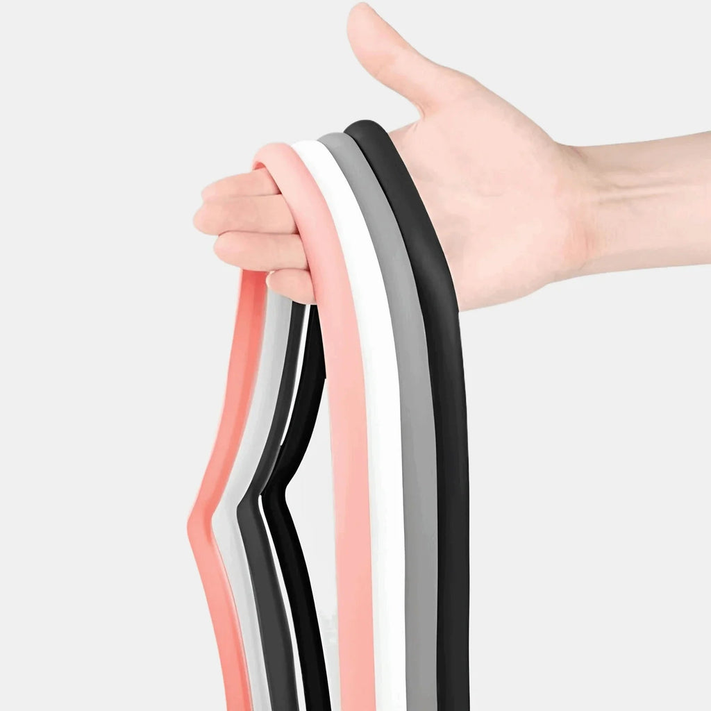 Hand holding a set of professional latex resistance bands in pink, white, grey, and black.