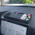 Black matte organizer tray on car dashboard holding eyeglasses and colorful decorative charms.