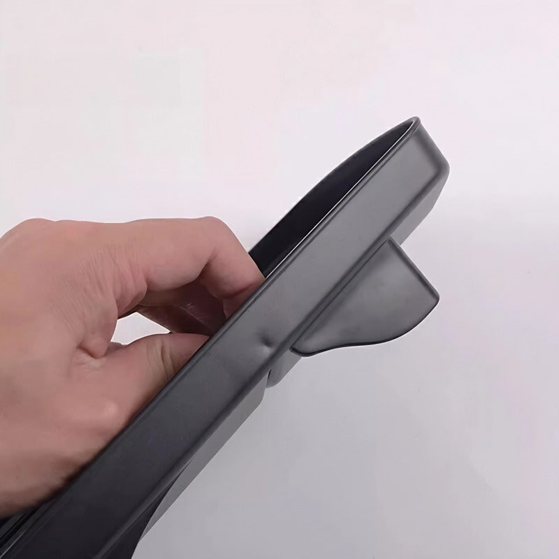Close-up of a hand touching a durable black rubber car floor mat with a raised edge design.