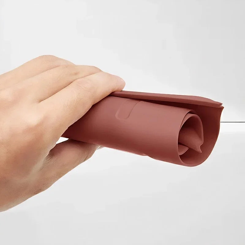 Flexible reddish-brown silicone car floor mat being bent to show durability.