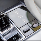 Glossy black center console control panel with silver metallic buttons and illuminated icons.