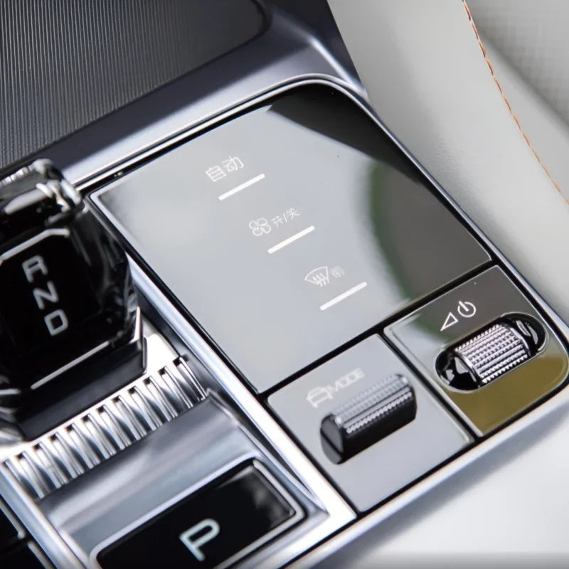 Glossy black center console control panel with silver metallic buttons and illuminated icons.