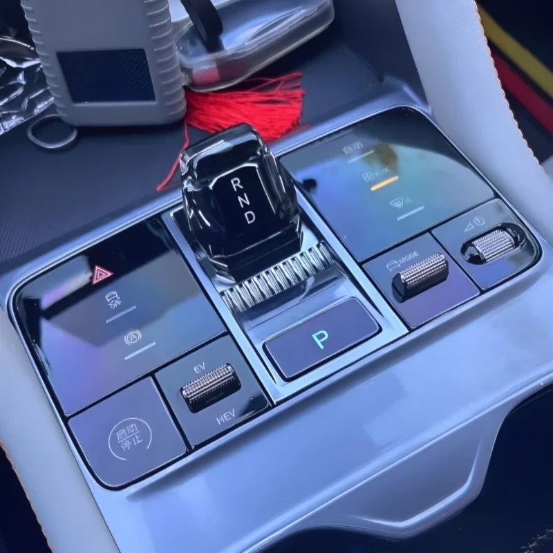 Glossy black electronic gear shifter with illuminated RND display and silver metallic controls.